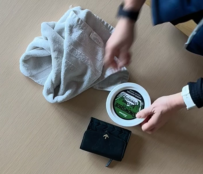 A time lapse video shows the application of Snowshoe Brand Leather Conditioner to a wallet. 